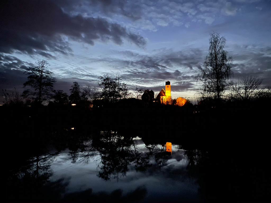 Die Gablinger Kirche spiegelt sich in der Schmutter in der Abenddämmerung